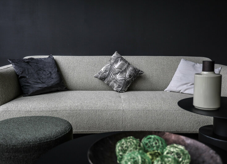 Schlichte Einrichtung Graues Sofa vor schwarzer Wand