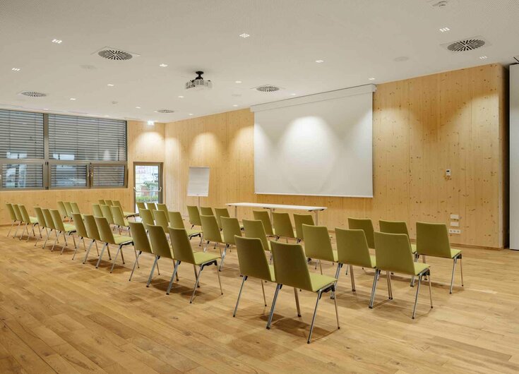 Seminarraum mit Stühlen, Leinwand, Beamer und Flipchart