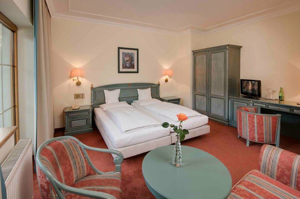 Zimmer Reschenhof Hotelbett mit Tisch und Sesseln