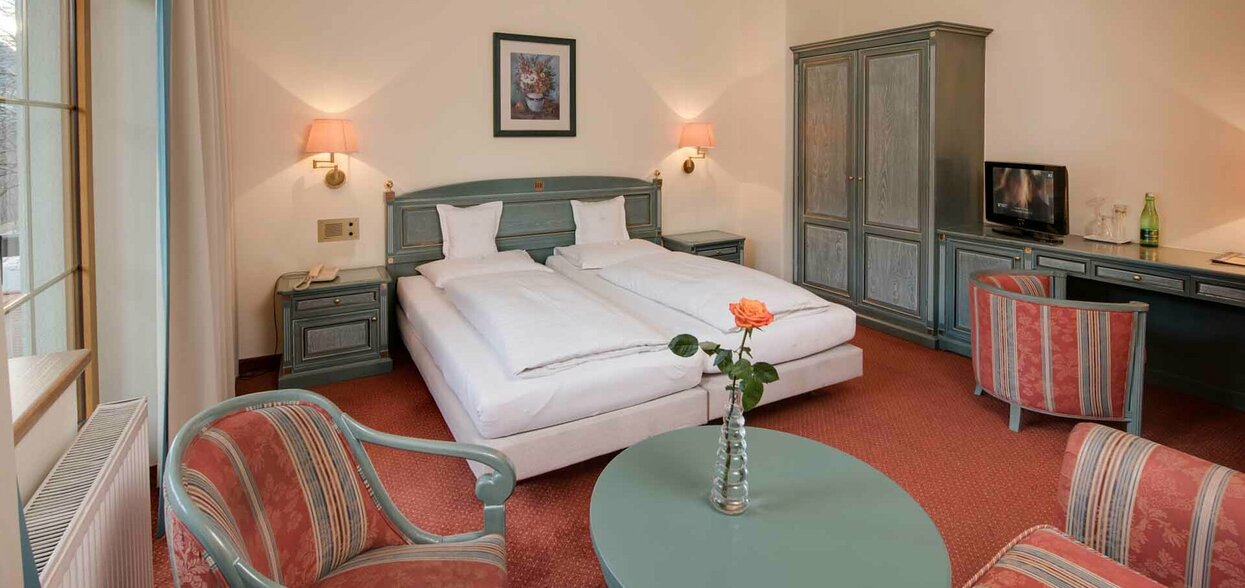 Zimmer Reschenhof Hotelbett mit Tisch und Sesseln
