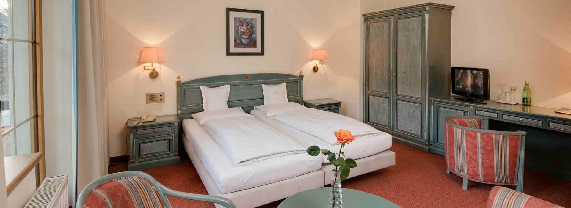 Zimmer Reschenhof Hotelbett mit Tisch und Sesseln