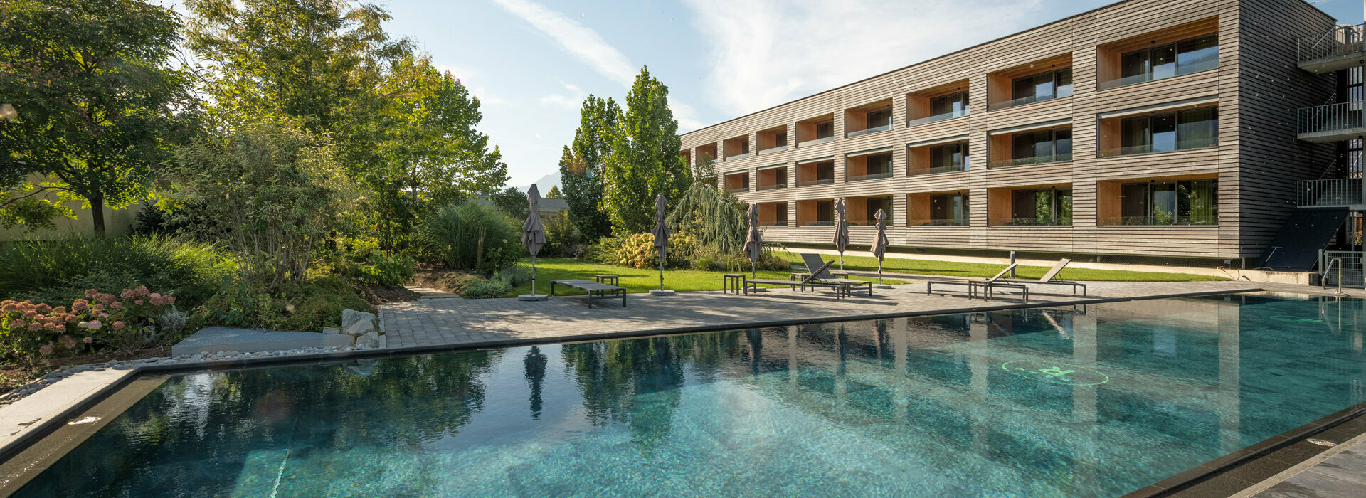 25-Meter Sportbecken in Mils Sportbecken mit modernen Gartensuiten im Hintergrund