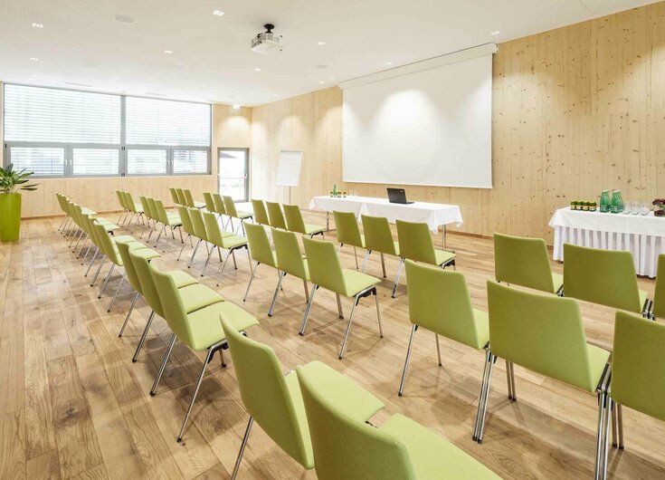 Seminarraum mit Stühlen, Leinwand, Beamer, Flipchart und Getränketisch