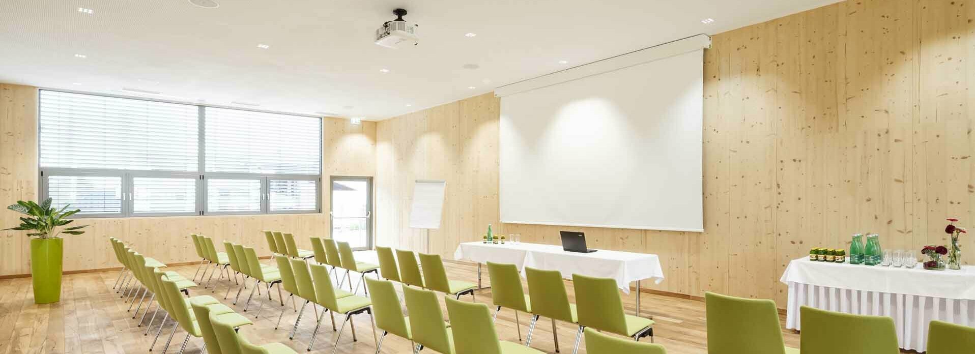 Seminarhotel in Mils in Tirol Seminarraum mit Stühlen, Leinwand, Beamer, Flipchart und Getränketisch