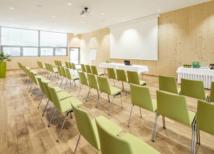 Seminarraum mit Stühlen, Leinwand, Beamer, Flipchart und Getränketisch