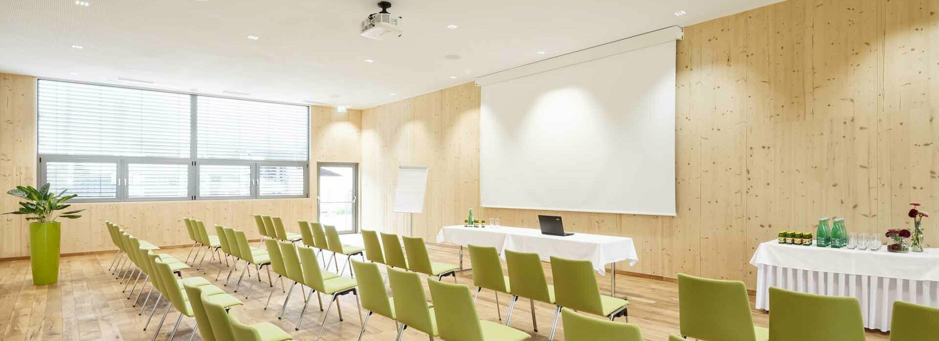 Seminarhotel in Mils in Tirol Seminarraum mit Stühlen, Leinwand, Beamer, Flipchart und Getränketisch