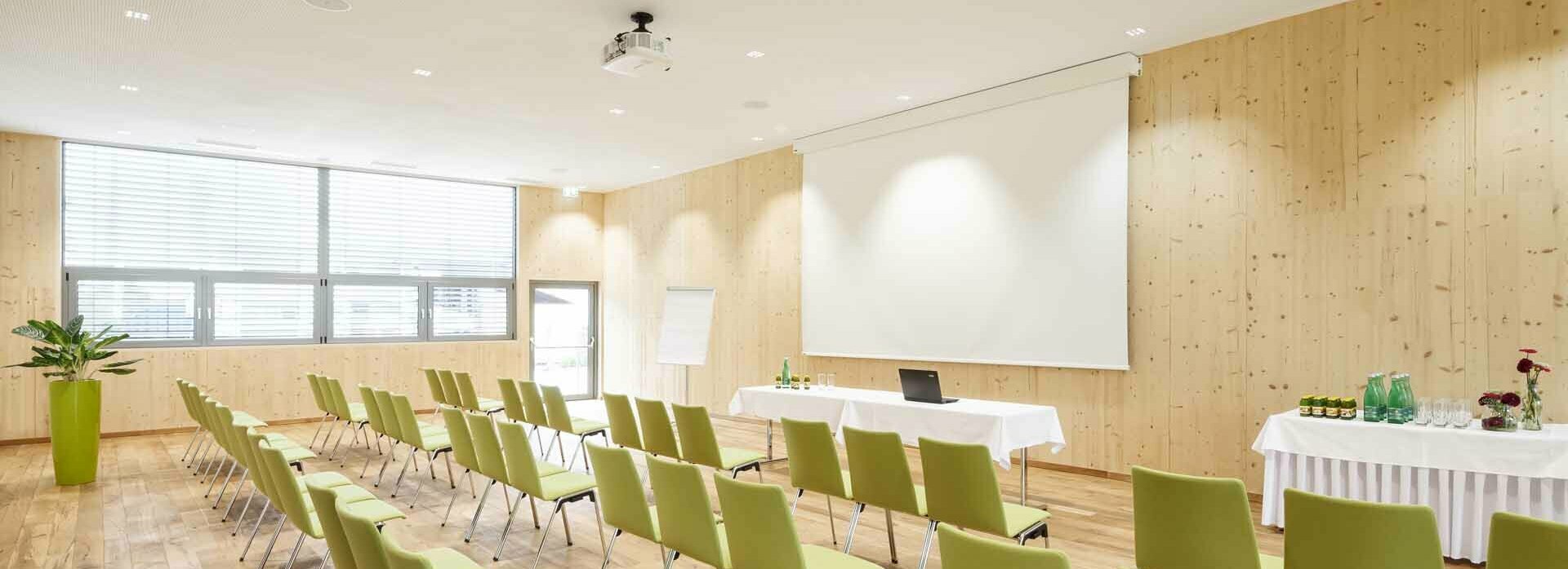 Seminarraum mit Stühlen, Leinwand, Beamer, Flipchart und Getränketisch