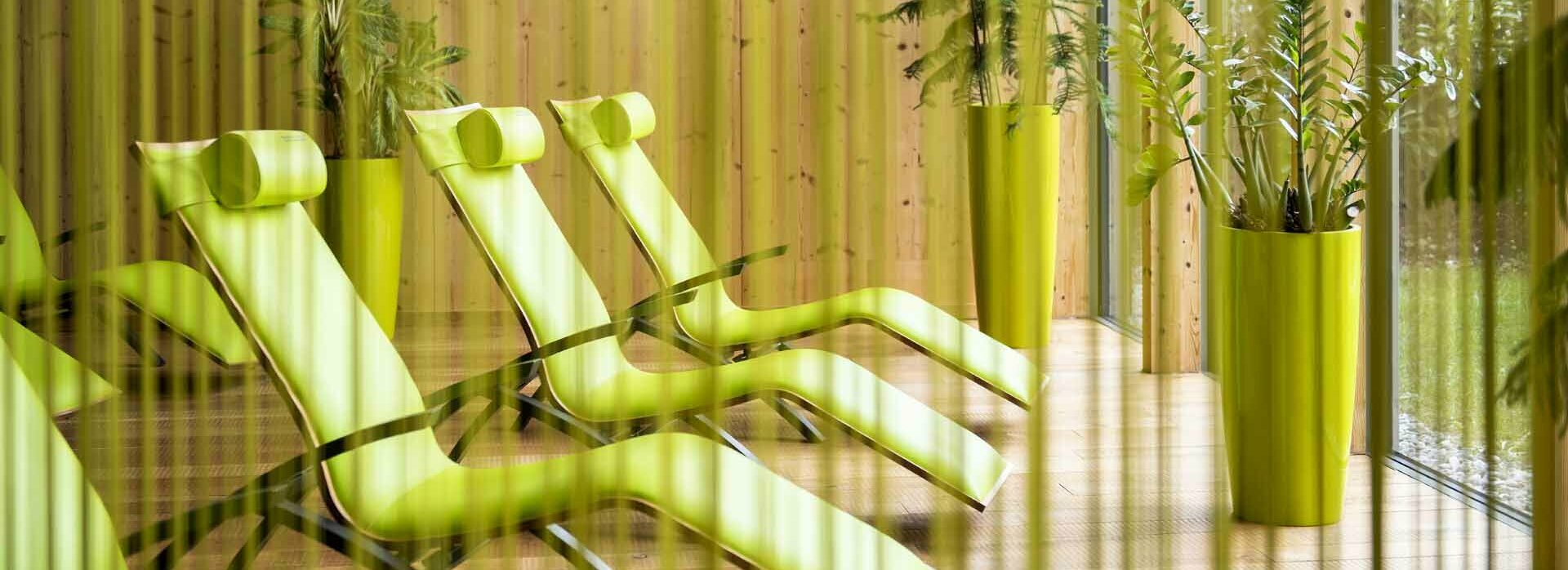 Liegestühle mit Grünpflanzen hinter Fadenvorhang