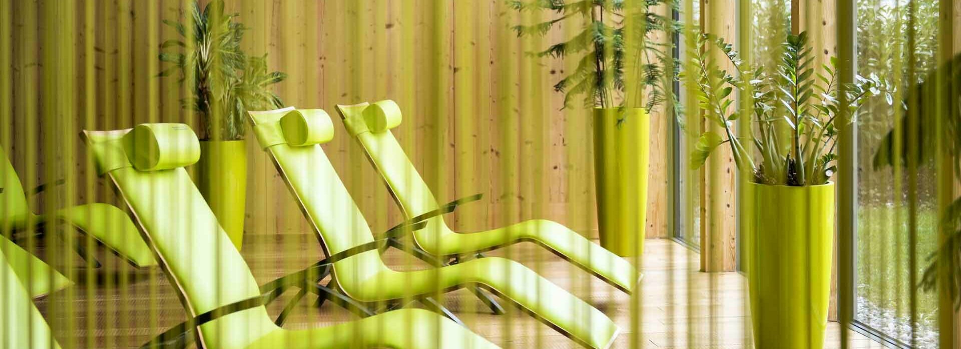 Liegestühle mit Grünpflanzen hinter Fadenvorhang