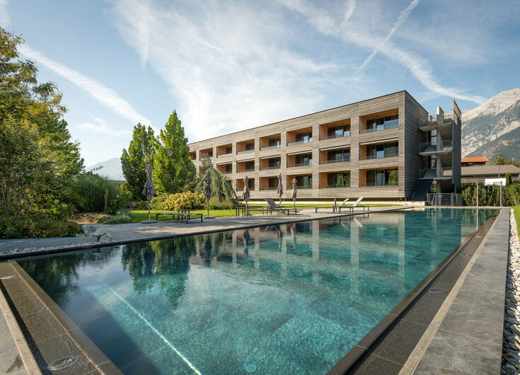 Sportbecken mit den Gartensuiten und Bergen im Hintergrund