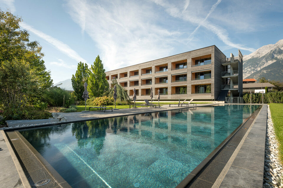 Außenpool Sportbecken mit den Gartensuiten und Bergen im Hintergrund