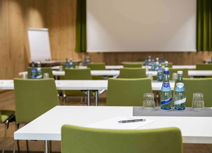 Seminare im Hotel Reschenhof Seminarraum mit Leinwand, Flipchart, Tischen, Schreibbedarf und Wasser