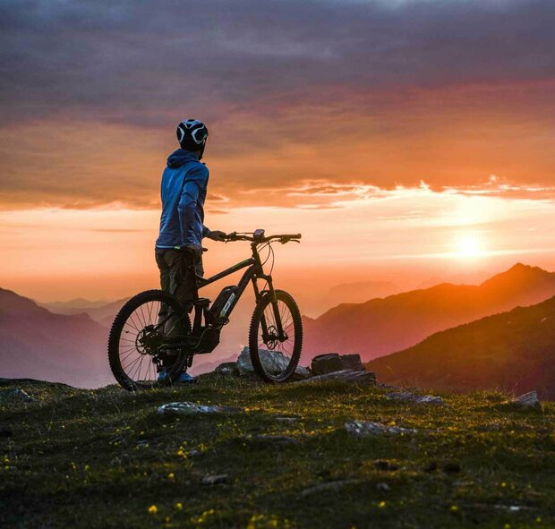 E-Biking & Biking E-Biker bewundert Sonnenaufgang auf dem Gipfel des Glungezer