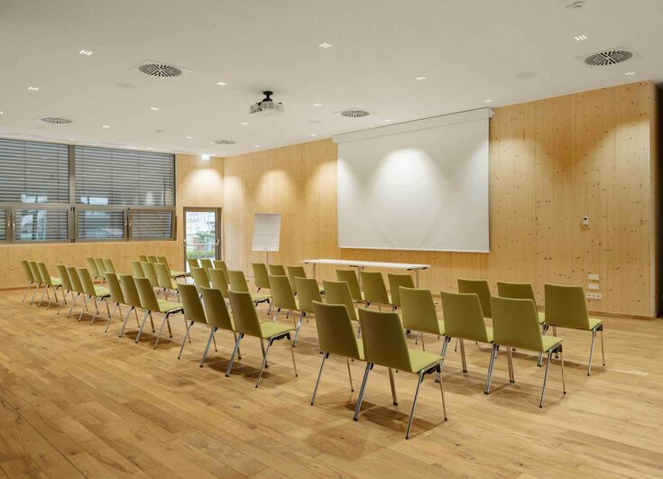 Seminare im Reschenhof Seminarraum mit Stühlen, Leinwand, Beamer, Flipchart und Getränketisch