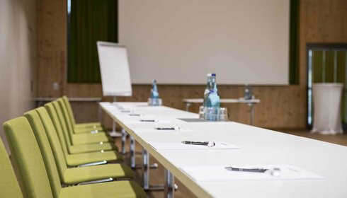 Seminars & conferences Tische mit Schreibbedarf und Wasser in Seminarraum